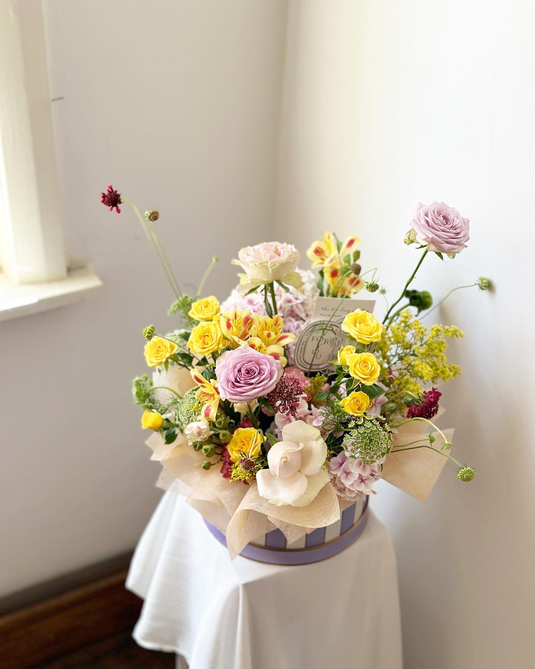round hat box filled with an assortment of colorful flowers
